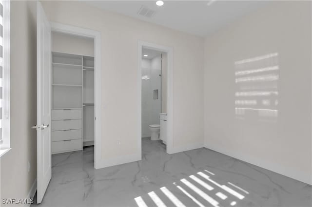 unfurnished bedroom featuring ensuite bath, a walk in closet, and a closet