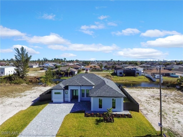 view of front of home with a front lawn, a garage, and a water view