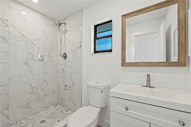 bathroom with tiled shower, vanity, and toilet