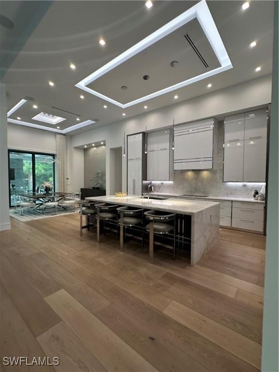 kitchen with white cabinetry, a large island, and light wood-type flooring