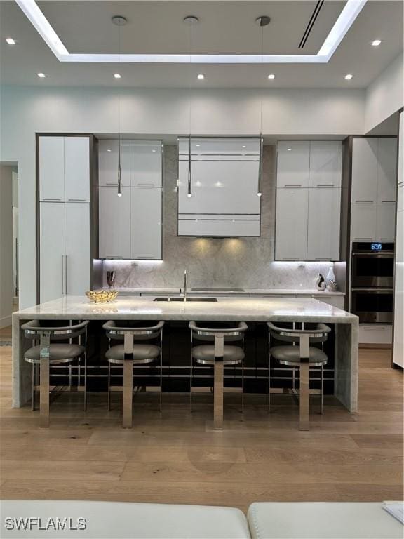 kitchen featuring a breakfast bar area, backsplash, a large island, and light wood-type flooring