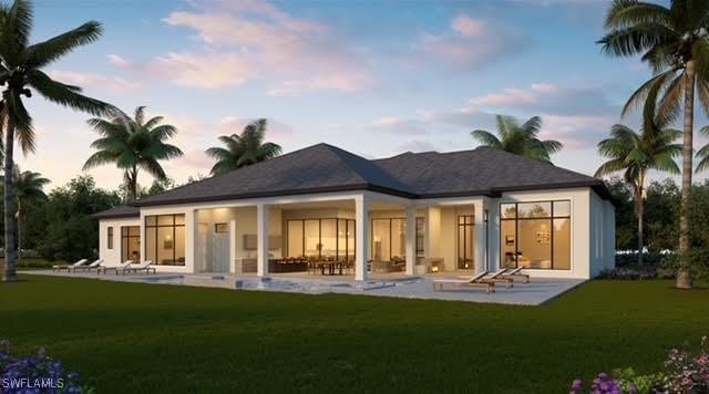 back house at dusk with a patio area and a lawn