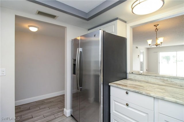 kitchen featuring a notable chandelier, light stone countertops, stainless steel fridge with ice dispenser, white cabinetry, and decorative light fixtures