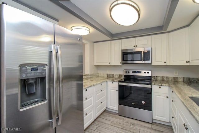 kitchen featuring white cabinets, stainless steel appliances, and light stone countertops