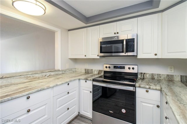 kitchen with light stone counters, white cabinets, and stainless steel appliances