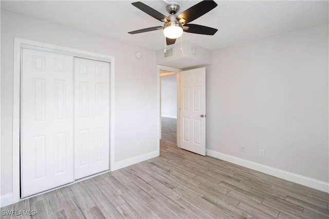 unfurnished bedroom featuring ceiling fan, a closet, and light wood-type flooring