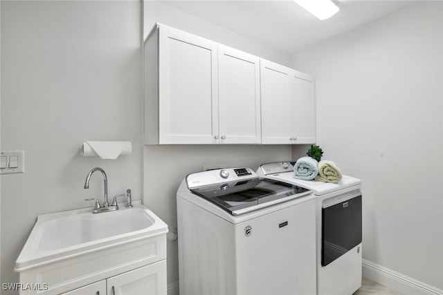 laundry room with washer and dryer, cabinet space, baseboards, and a sink