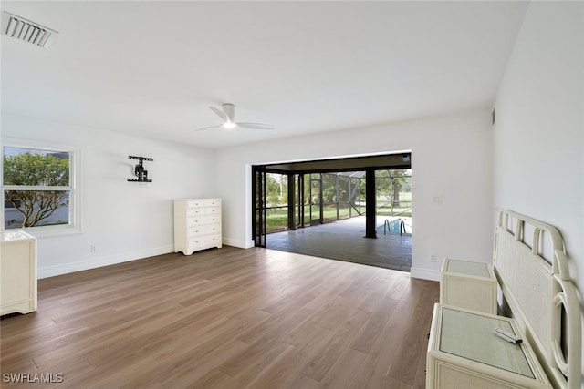 unfurnished living room featuring baseboards, wood finished floors, visible vents, and a healthy amount of sunlight