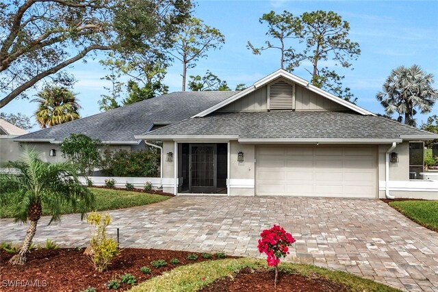 2037 Prince Dr, Naples, FL 34110 - ranch-style house featuring an attached garage, decorative driveway, stucco siding, and a shingled roof