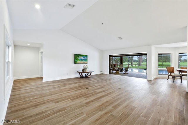 unfurnished living room featuring visible vents, baseboards, high vaulted ceiling, and light wood finished floors