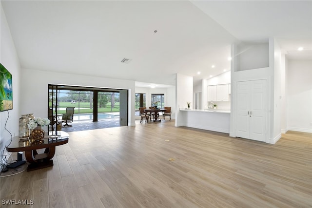 living area featuring visible vents, baseboards, high vaulted ceiling, recessed lighting, and light wood-type flooring