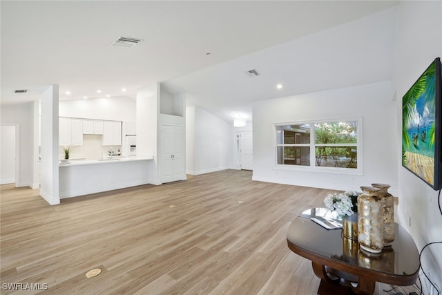 unfurnished living room featuring recessed lighting, visible vents, lofted ceiling, and light wood finished floors