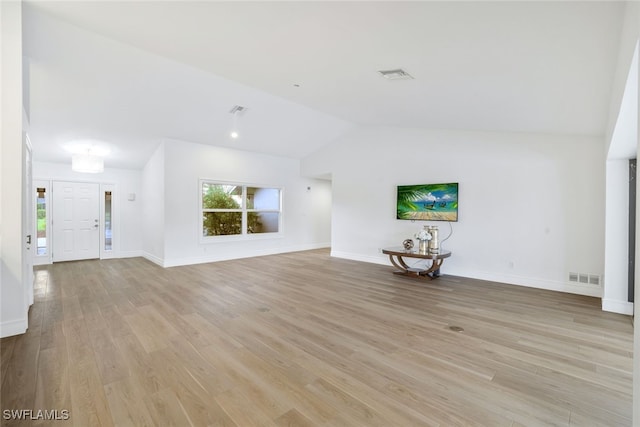 unfurnished living room with lofted ceiling, baseboards, visible vents, and light wood-type flooring