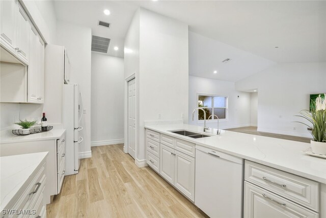 kitchen featuring lofted ceiling, white appliances, white cabinets, sink, and light hardwood / wood-style floors