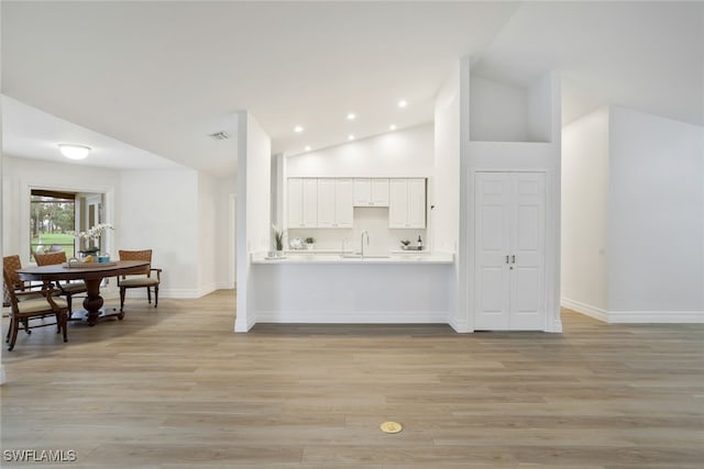 kitchen featuring white cabinetry, light countertops, light wood-style flooring, and baseboards