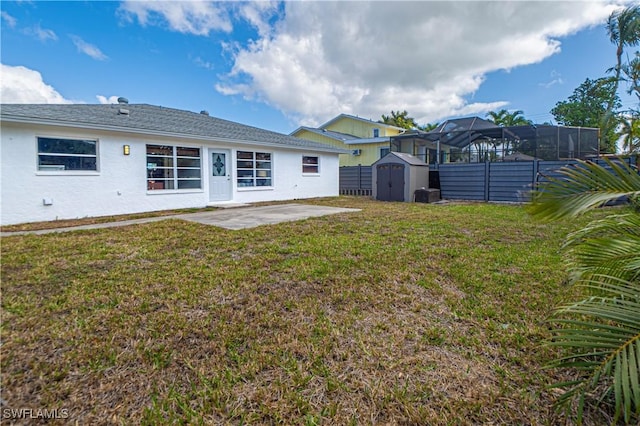 back of property featuring a lawn, a storage shed, and a patio