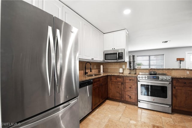 106 Pago Pago Dr W, Naples, FL 34113 - kitchen featuring appliances with stainless steel finishes, a sink, light stone counters, stone tile flooring, and recessed lighting