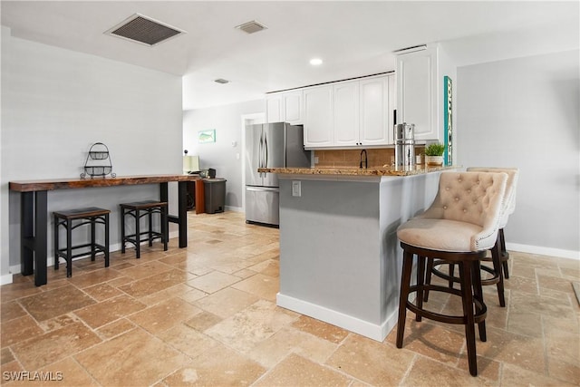 106 Pago Pago Dr W, Naples, FL 34113 - kitchen featuring freestanding refrigerator, stone tile flooring, a kitchen bar, white cabinets, and baseboards