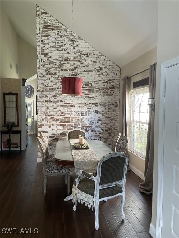 dining space featuring dark hardwood / wood-style floors and high vaulted ceiling