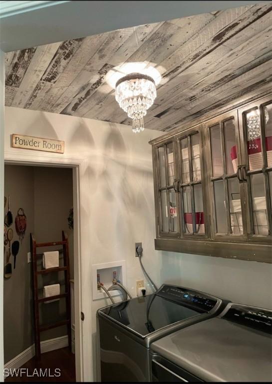 clothes washing area featuring washer and dryer, wooden ceiling, and an inviting chandelier