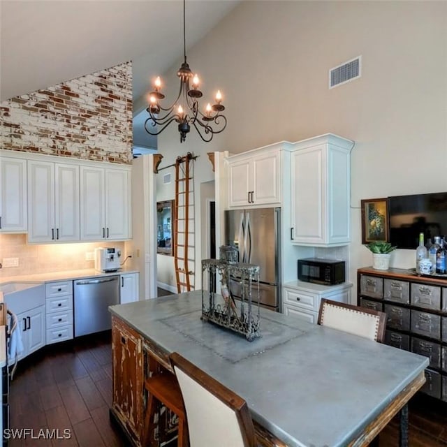 kitchen featuring white cabinetry, pendant lighting, high vaulted ceiling, and stainless steel appliances