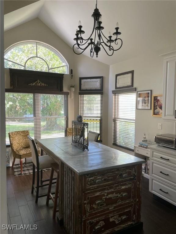 kitchen with lofted ceiling, dark hardwood / wood-style flooring, white cabinetry, and an inviting chandelier