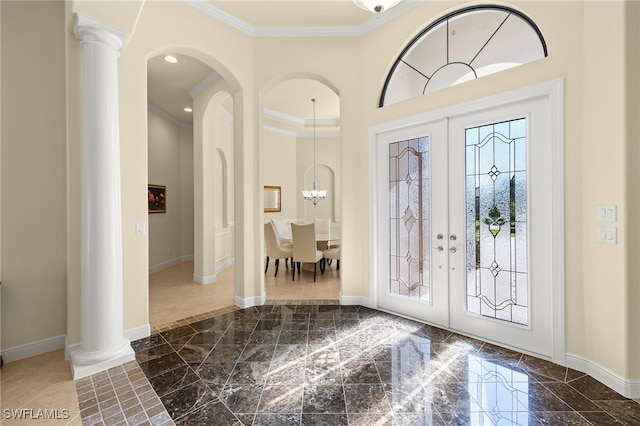 foyer entrance featuring crown molding, french doors, and an inviting chandelier