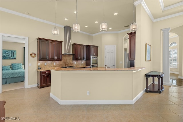 kitchen featuring backsplash, crown molding, hanging light fixtures, wall chimney exhaust hood, and decorative columns