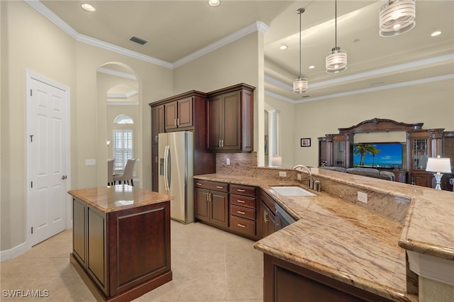 kitchen featuring stainless steel fridge, backsplash, ornamental molding, sink, and hanging light fixtures