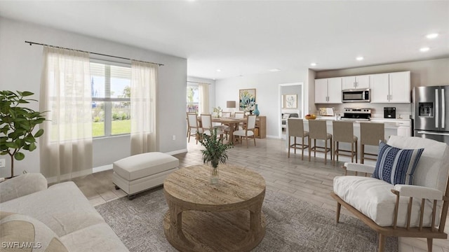 living area featuring light wood-type flooring, baseboards, and recessed lighting