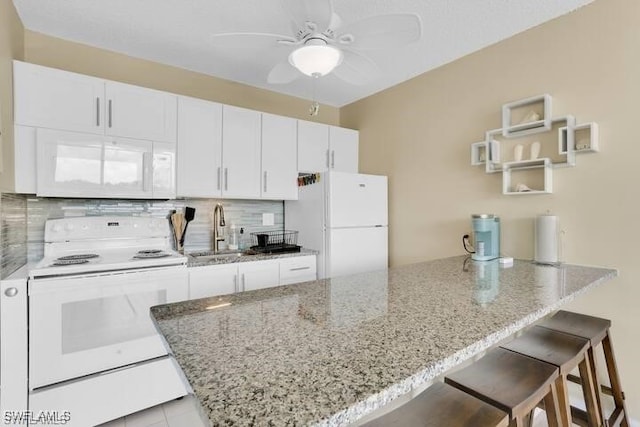 kitchen featuring sink, a kitchen breakfast bar, white appliances, decorative backsplash, and white cabinets