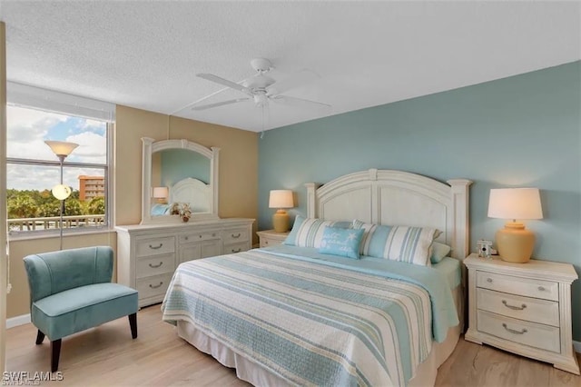 bedroom featuring ceiling fan, light hardwood / wood-style flooring, and a textured ceiling