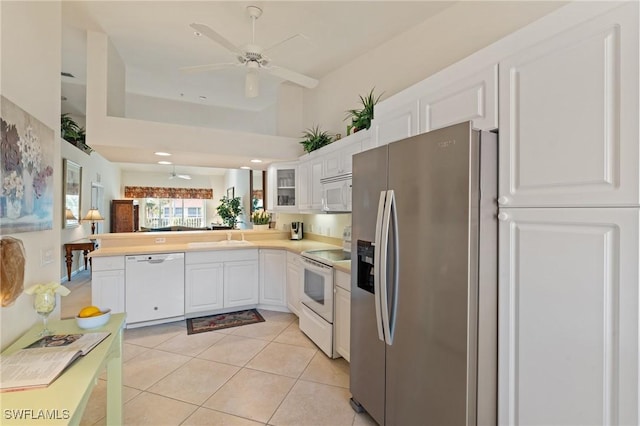 kitchen featuring kitchen peninsula, light tile patterned floors, white cabinets, and white appliances