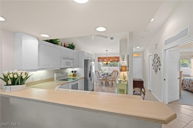 kitchen featuring kitchen peninsula, white cabinetry, a healthy amount of sunlight, and white appliances