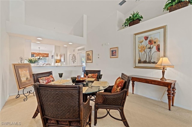 dining space with a high ceiling, light colored carpet, and an inviting chandelier