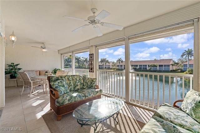 sunroom with ceiling fan and a water view