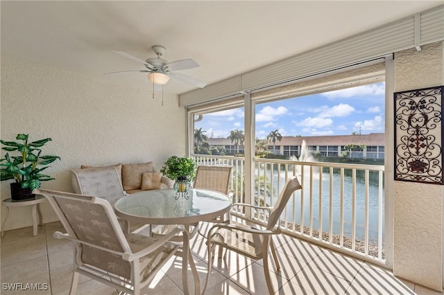 sunroom / solarium featuring a water view and ceiling fan