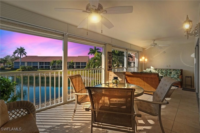 sunroom / solarium with a water view, ceiling fan, and a healthy amount of sunlight