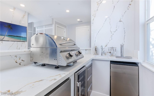 kitchen with stainless steel refrigerator, sink, white cabinets, and wine cooler