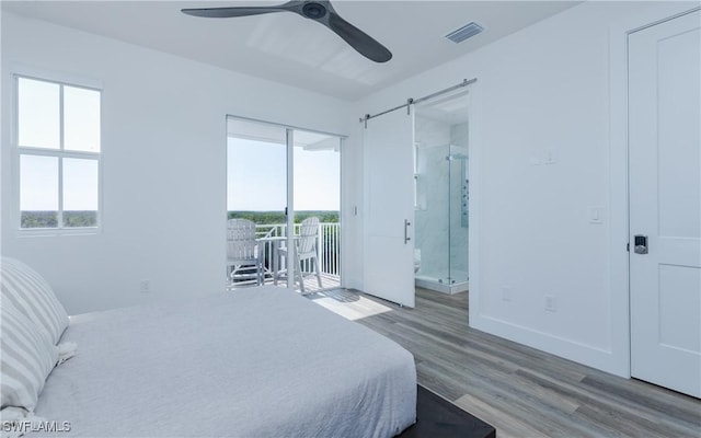 bedroom featuring connected bathroom, ceiling fan, a barn door, access to outside, and light wood-type flooring