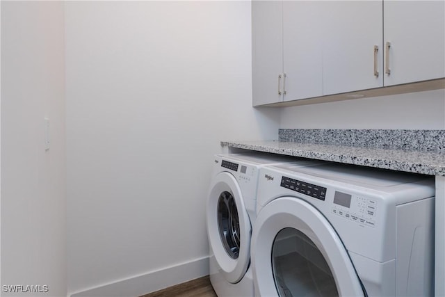 laundry room with cabinets, washer and dryer, and dark hardwood / wood-style flooring