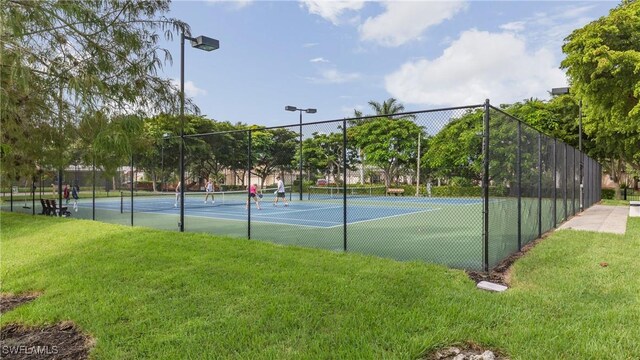 view of tennis court featuring a yard