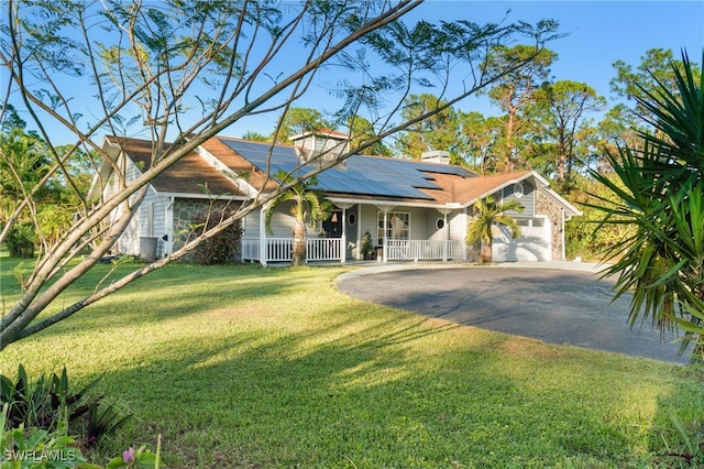 ranch-style home with solar panels, a garage, covered porch, and a front yard