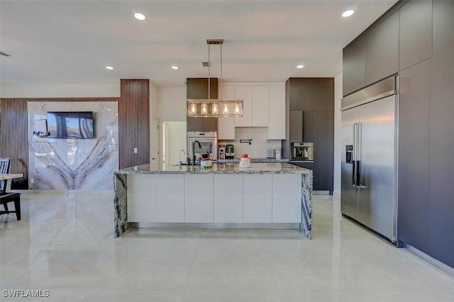 kitchen featuring decorative light fixtures, decorative backsplash, a large island, light stone counters, and stainless steel appliances