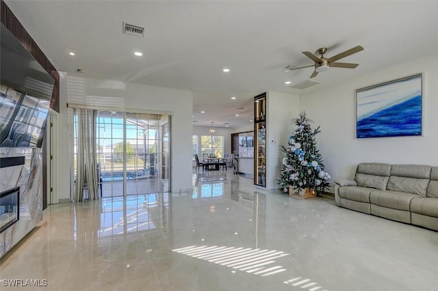 living room featuring ceiling fan and a premium fireplace