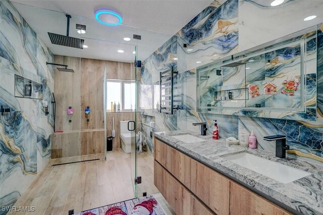 bathroom with backsplash, wood-type flooring, an enclosed shower, toilet, and vanity