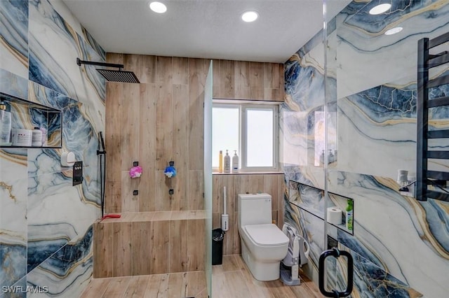 bathroom with wood-type flooring, toilet, walk in shower, and wooden walls