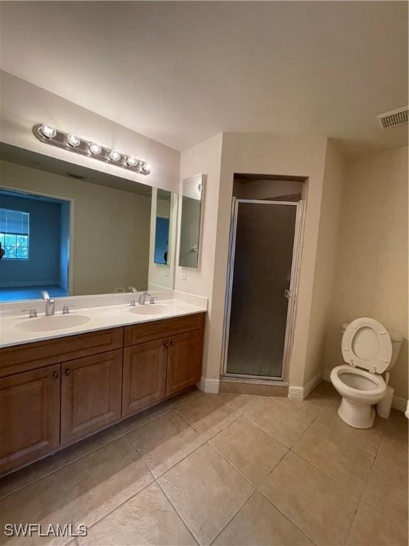 bathroom featuring tile patterned flooring, vanity, toilet, and a shower with shower door