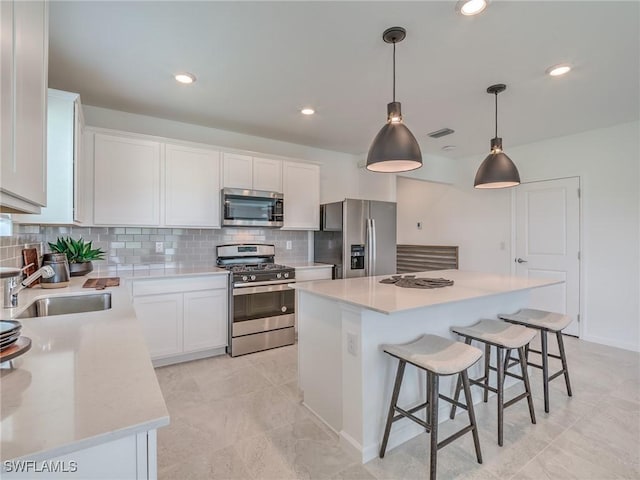 kitchen with sink, decorative light fixtures, a center island, white cabinetry, and appliances with stainless steel finishes