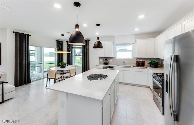 kitchen with appliances with stainless steel finishes, white cabinetry, sink, and a kitchen island